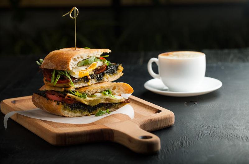 黑色桌上的美味三明治和一杯咖啡