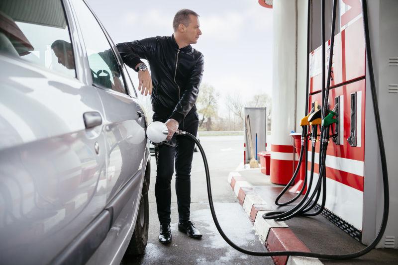 年轻男子站在加油站加油