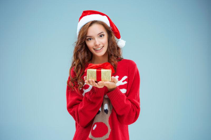 穿着圣诞帽的女孩拿着圣诞礼物