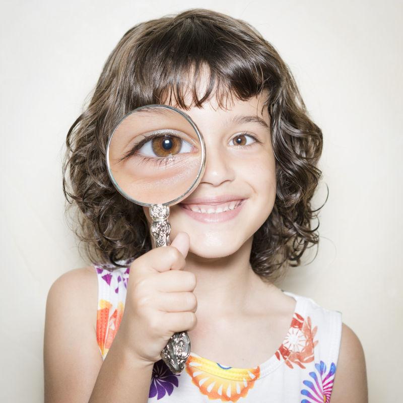 拿着放大镜的卷发小女孩