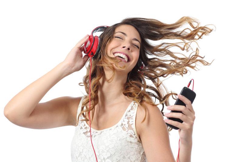 白色背景下跟着手机音乐摇摆的女孩