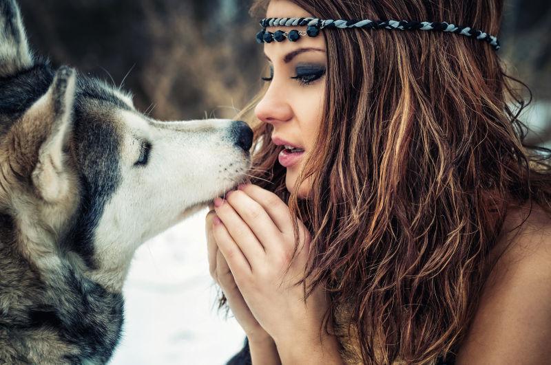 可爱的女孩在雪白的树林里和西伯利亚哈士奇一起玩耍