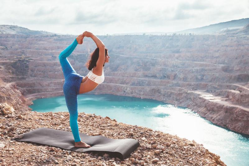 蓝色湖边锻炼瑜伽的金发美女