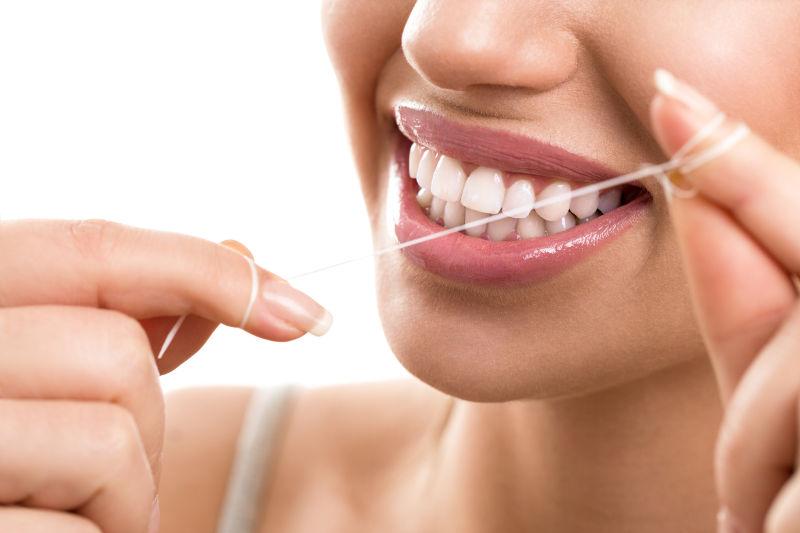 拿着牙线清洁牙齿的美女