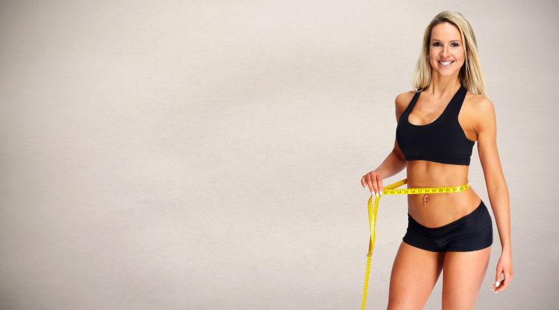 健身美女在用皮尺量自己的腰围