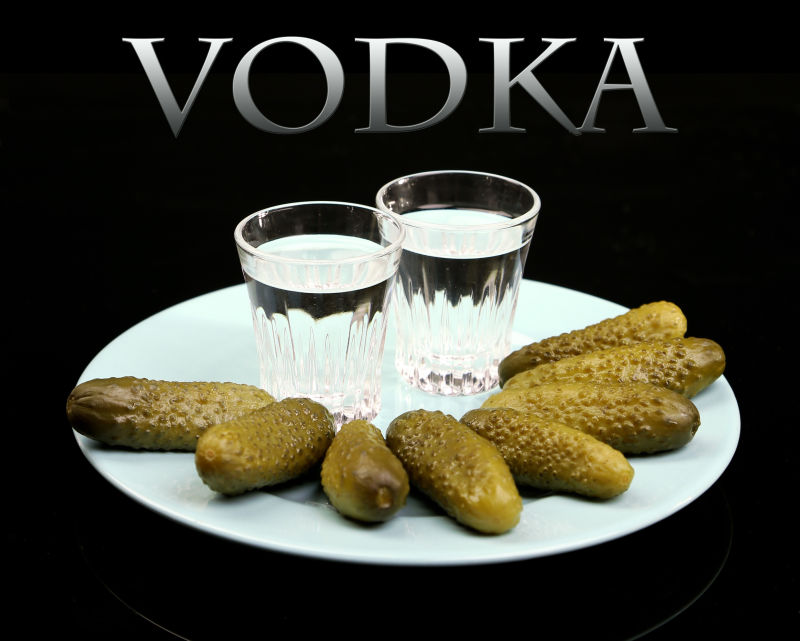 黑色背景下盘子里玻璃杯与伏特加腌制的泡菜