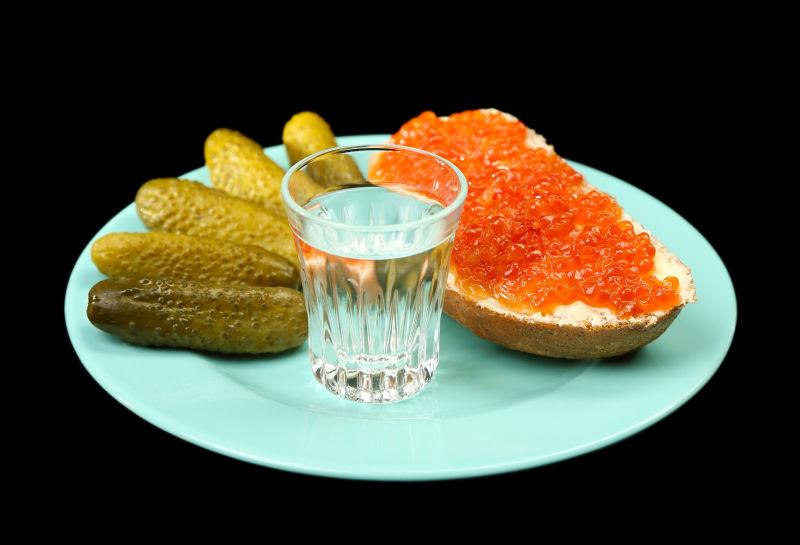 盘子里的鱼子酱与玻璃杯伏特加泡制的蔬菜