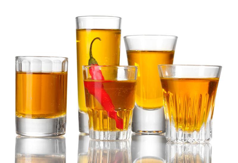 白色背景上的五杯伏特加和红辣椒