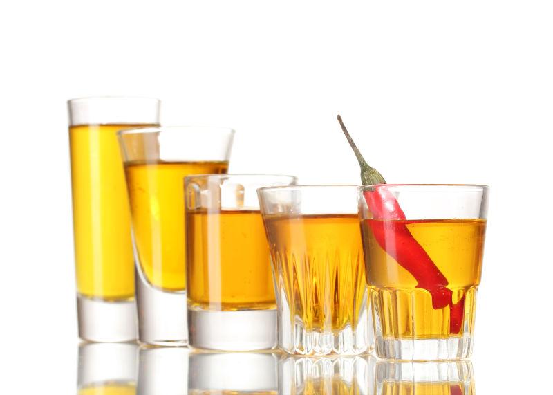 白色背景前杯子里的伏特加和辣椒