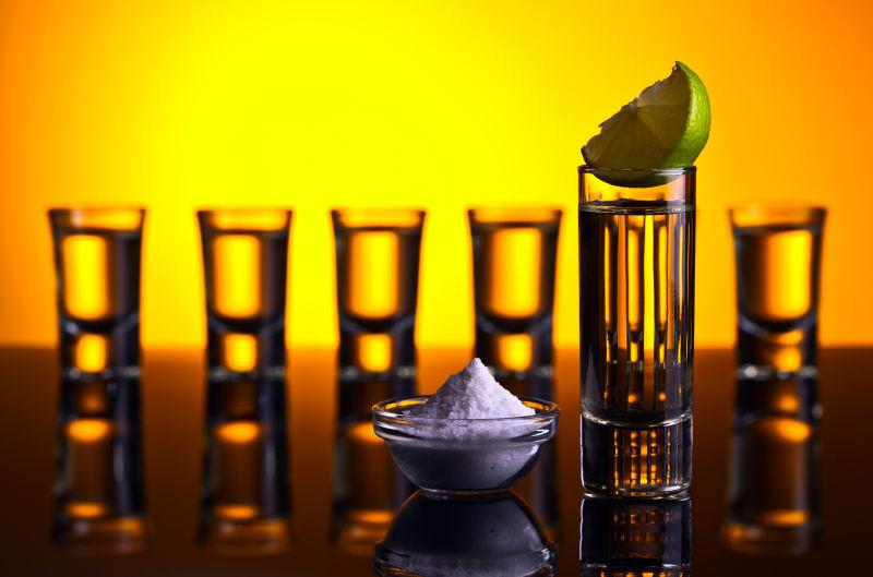 黑色反射背景中的金龙舌兰酒与青柠石灰