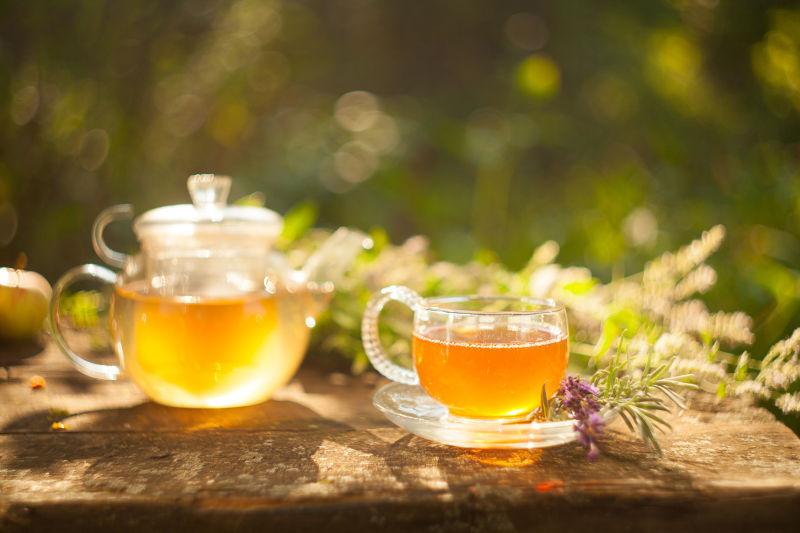 阳光照射下木桌上盛满茶水的茶具