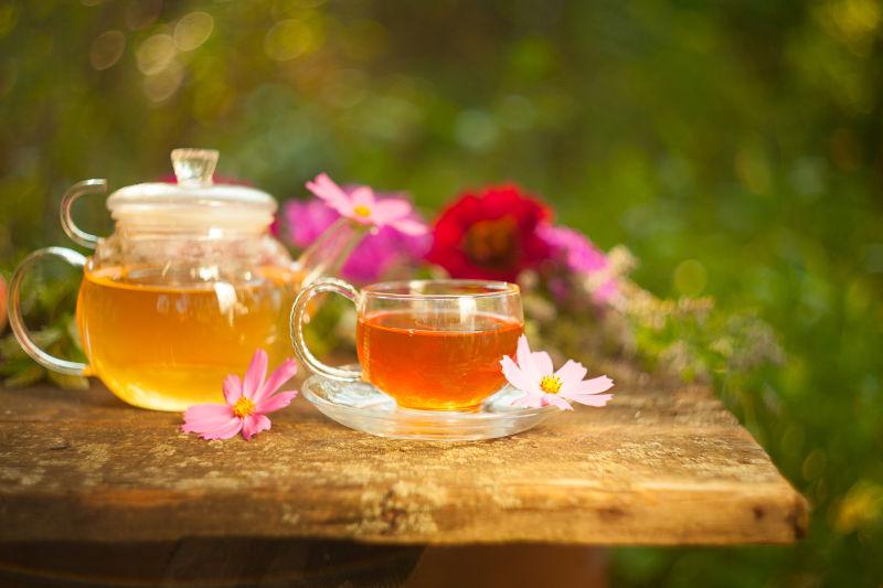 户外木桌上鲜花围绕的透明茶具
