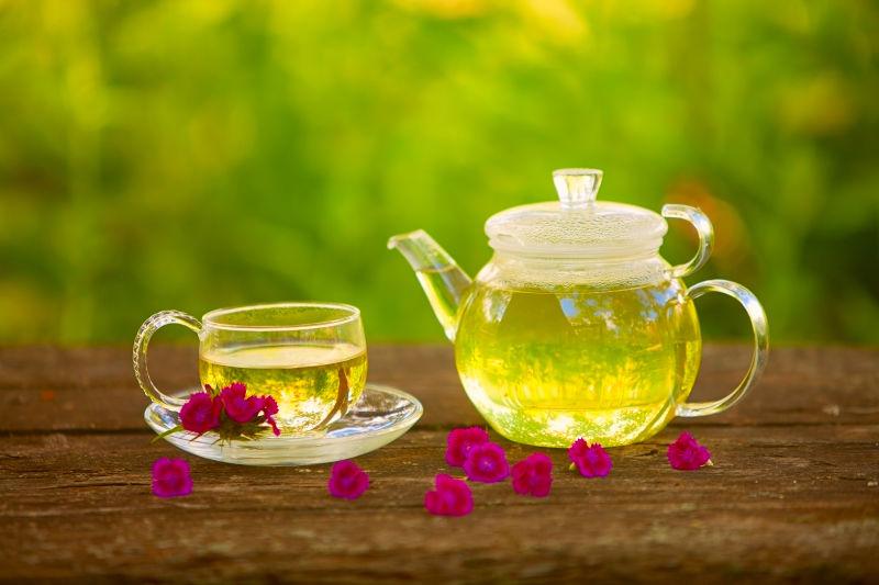 木桌上的小花和旁边的绿茶