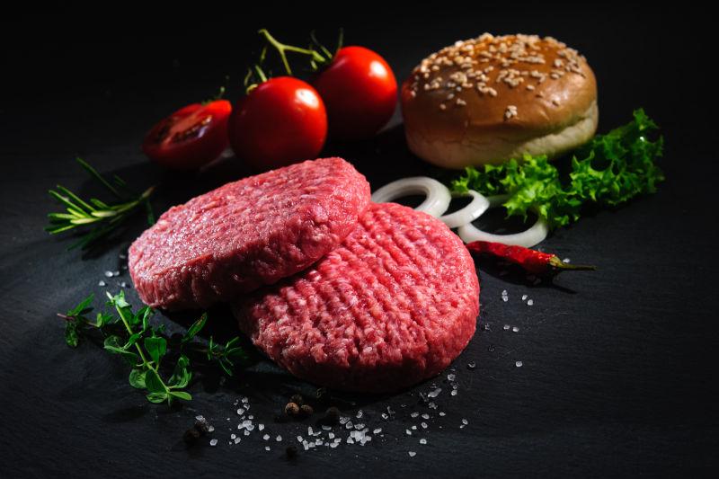 黑背景中牛肉肉饼和其他汉堡包的配料