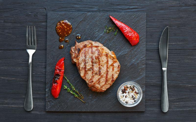 黑木桌上等待食用的美味烤牛排