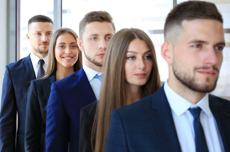 在办公室里排成一行的快乐微笑的商业团队