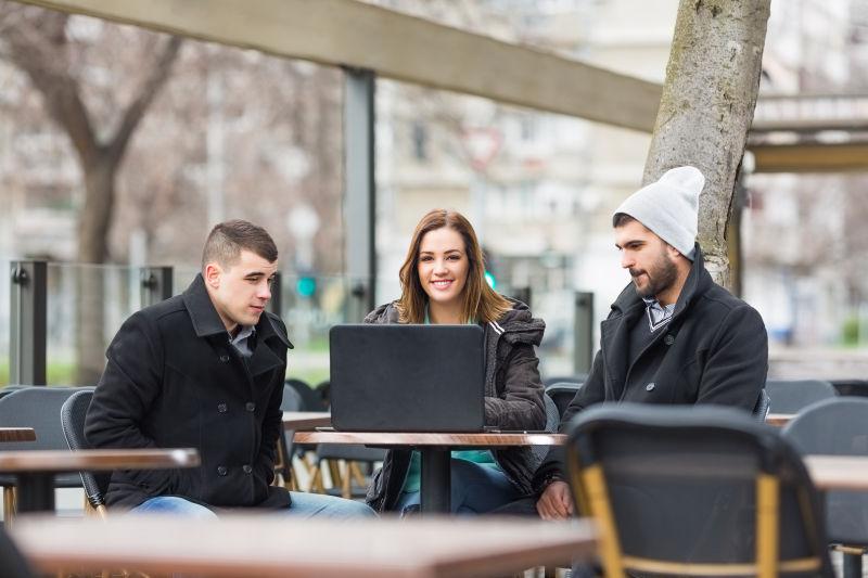 露台咖啡桌上的笔记本和三个年轻的大学生