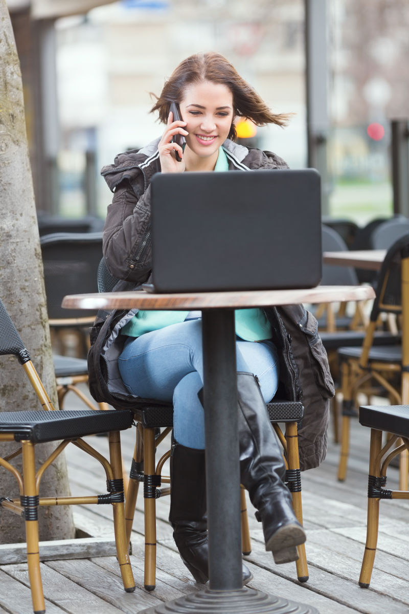 露台咖啡桌边使用笔记本的美女