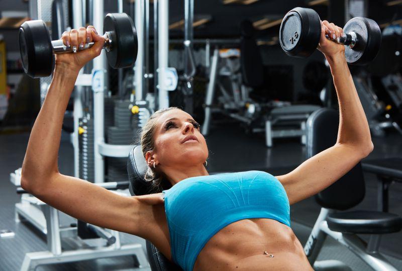 年轻女子在健身房锻炼哑铃