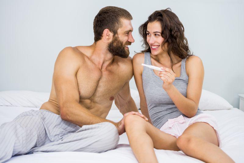 白色床上一对夫妻拿着测孕棒