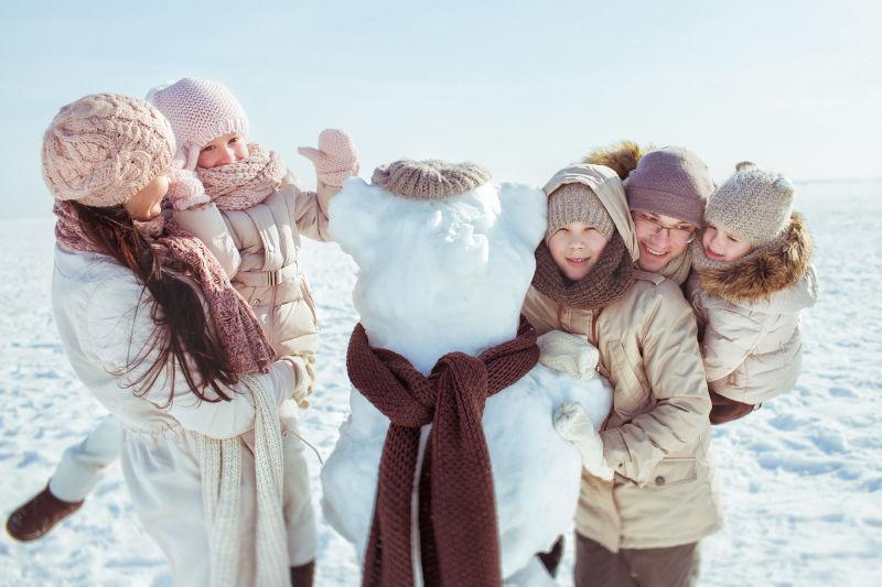 在戶外堆雪人的一家人