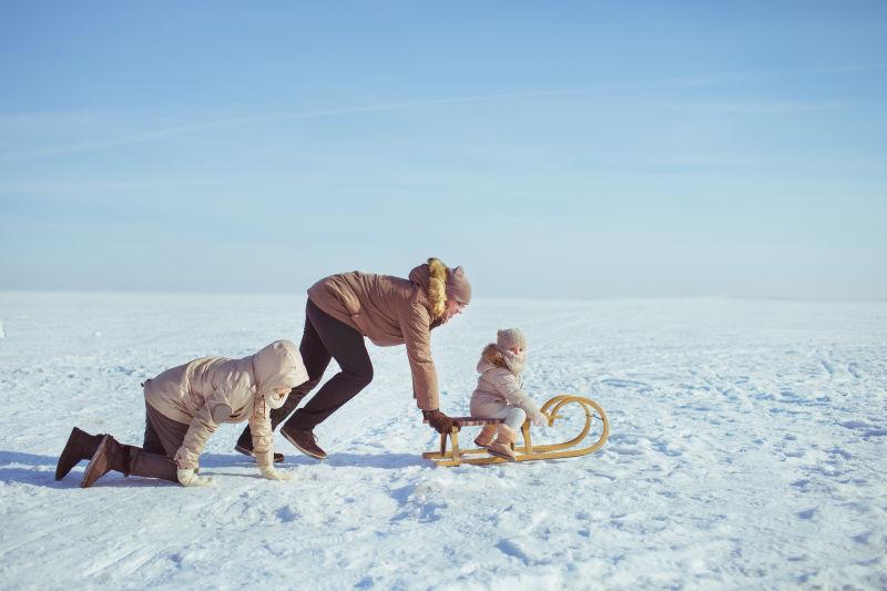 冬季雪地里父亲带着两个小孩玩耍