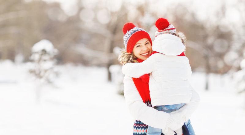 雪地里母亲抱着小女孩散步