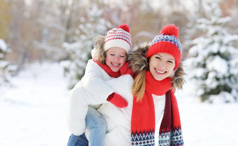 雪地里母亲背着小女孩玩耍