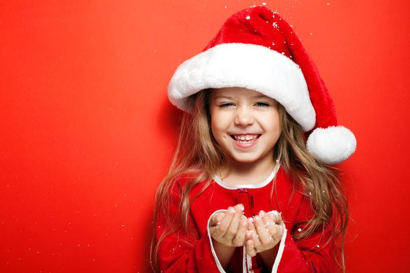 红色背景下戴着圣诞帽的小女孩