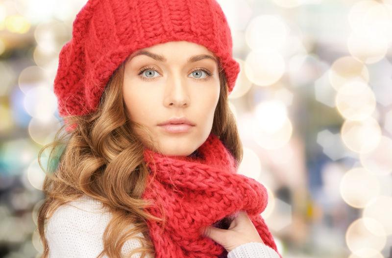 在圣诞节的背景下戴着红色帽子和围巾的年轻女子
