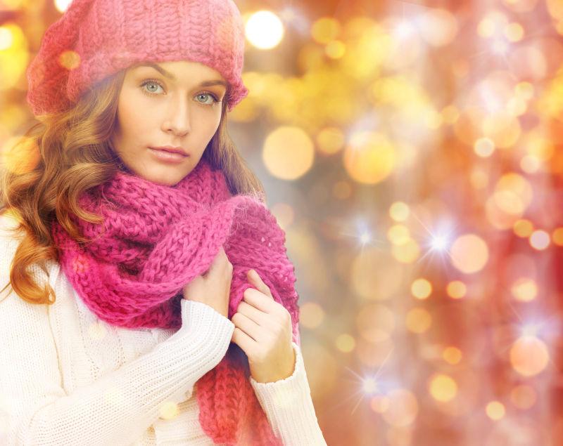 在圣诞灯的背景下戴着冬季帽子的年轻女子