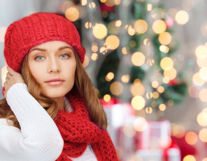 在冬季的圣诞节戴红帽和围巾的年轻女子