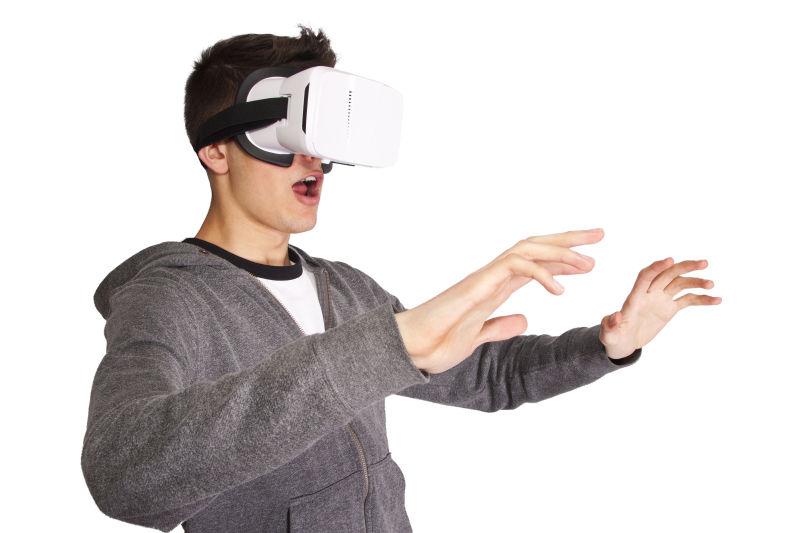 白色背景下戴着VR眼镜伸出双手的小伙子