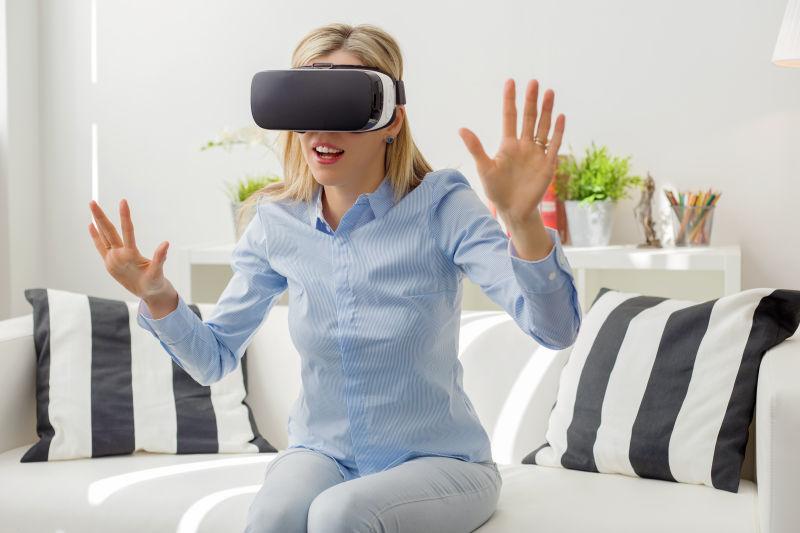 白色背景下坐在沙发上戴着3D眼镜-vr眼镜伸出双手的人