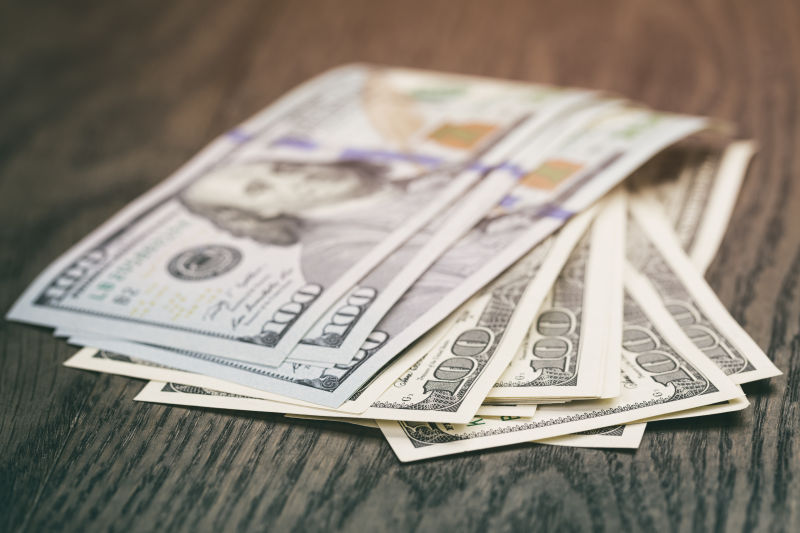 木桌上散落的百元钞票