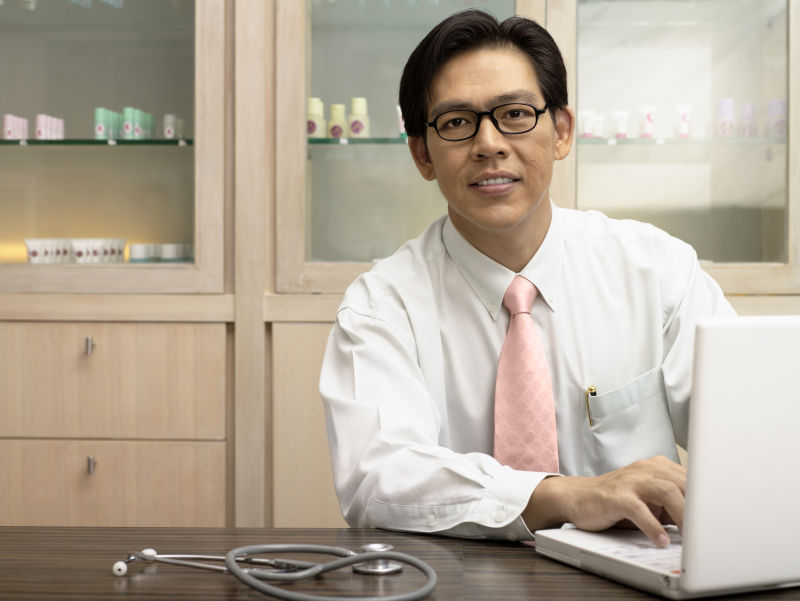 微笑的男医生使用笔记本电脑