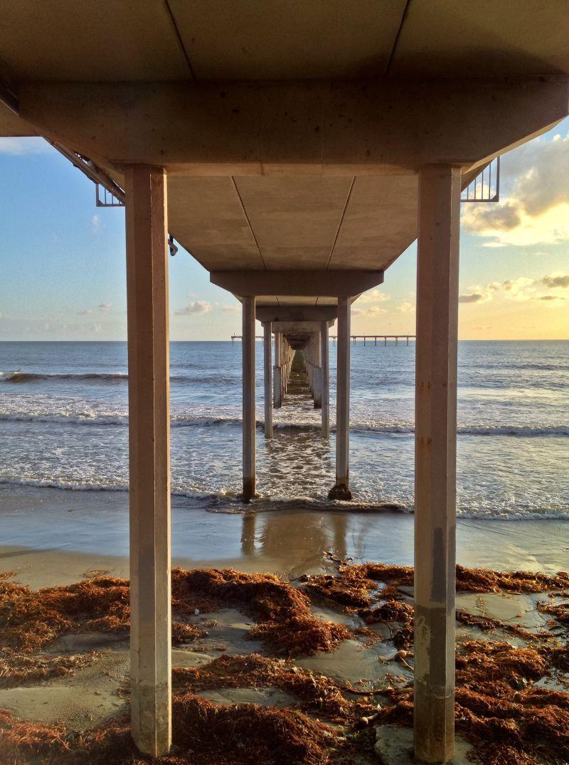 日落时分的海洋海滩码头的桥下