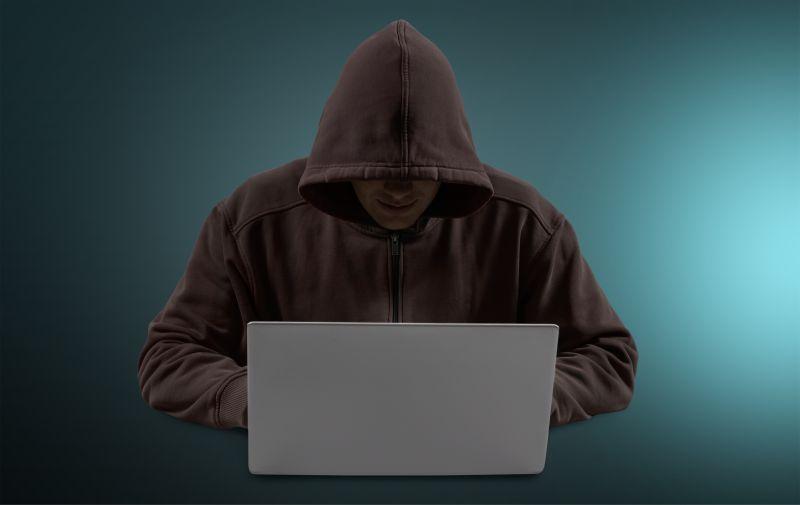 穿着黑色卫衣的计算机黑客在使用笔记本