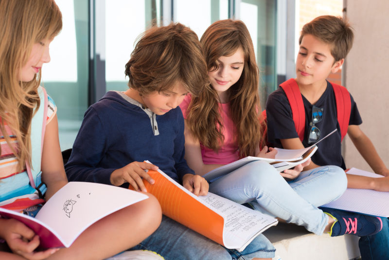 四个低头看着作业的小学生