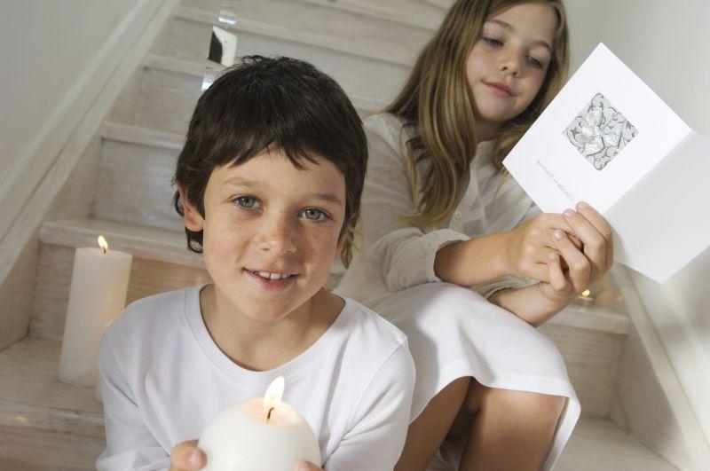 坐在楼梯上捧着蜡烛和贺卡的孩子