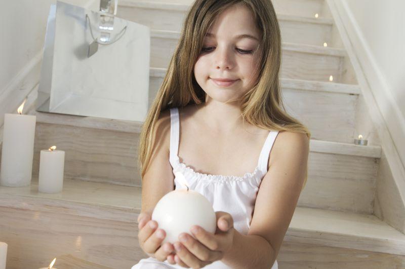 穿白色裙子坐在楼梯上的女孩子捧着蜡烛