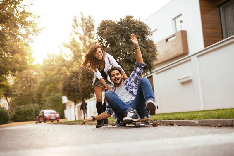 推着男朋友的女孩在玩滑板