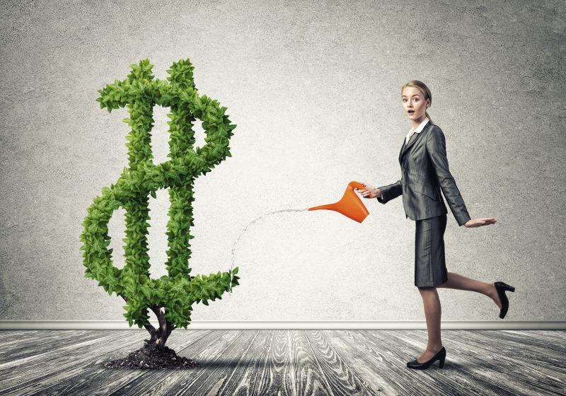 灰色背景下漂亮女商人浇灌经济的概念