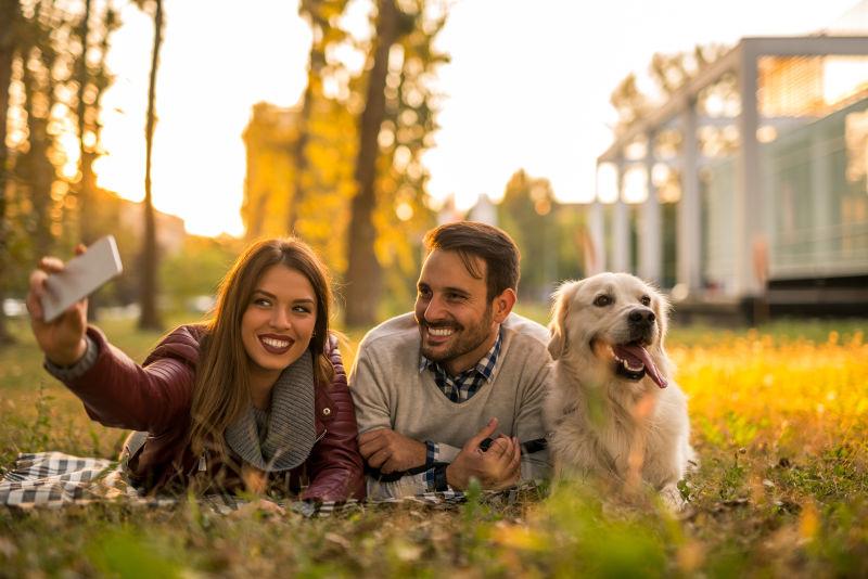 夫妇躺在草地上和自己的狗自拍