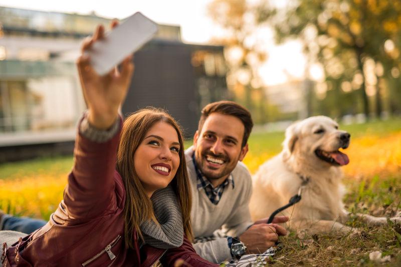 草地上自拍的情侣和狗狗