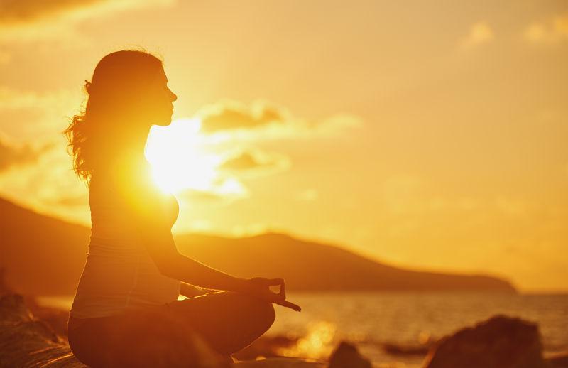 日落时沙滩上练瑜伽冥想的美女