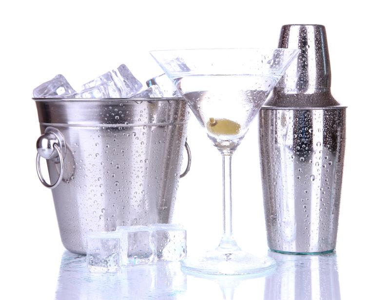 白色背景上装着冰块的金属冰桶旁放着鸡尾酒和摇酒壶