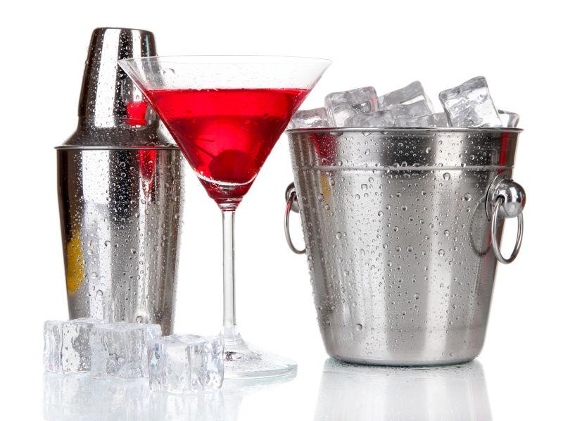 白色背景上鸡尾酒旁放着装满冰块的金属冰桶和摇酒壶