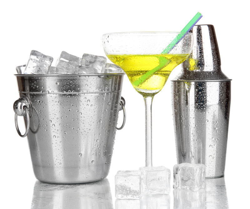 白色背景上装着冰块的金属冰桶旁放着摇酒壶和一杯鸡尾酒