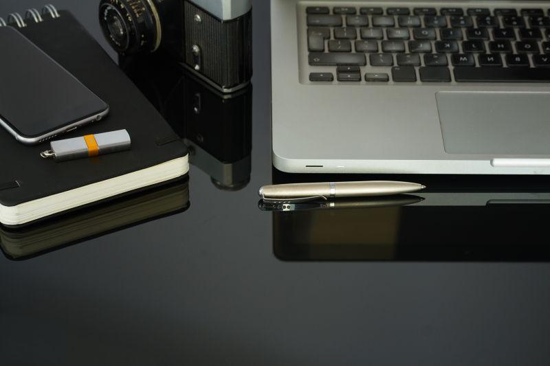 黑色玻璃桌上的笔记本电脑和手机